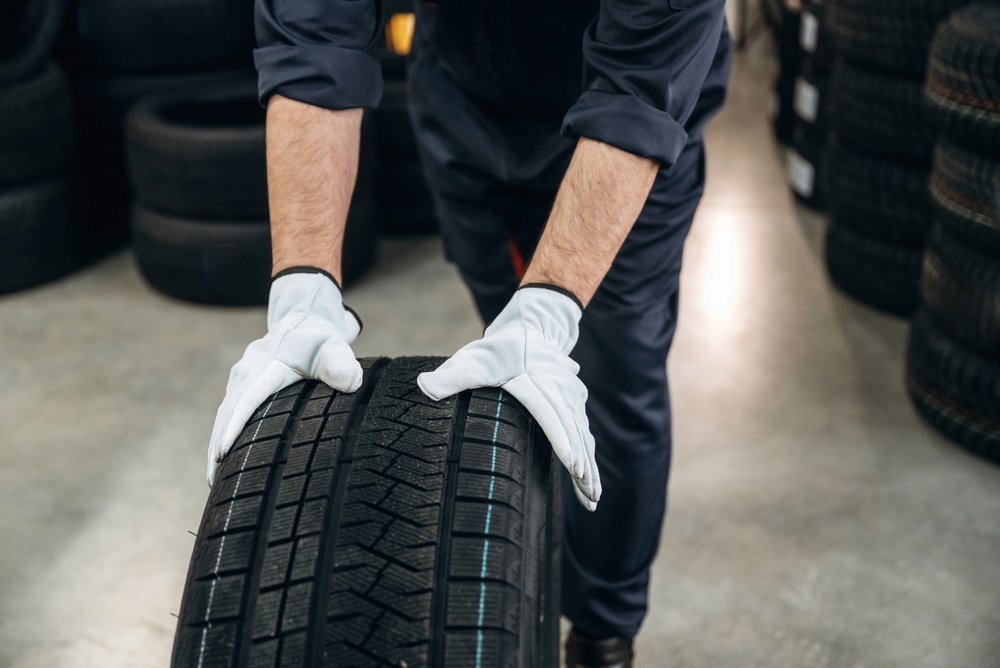 Male,Technician,In,Gloves,Lifts,A,Car,Tire,Inside,A